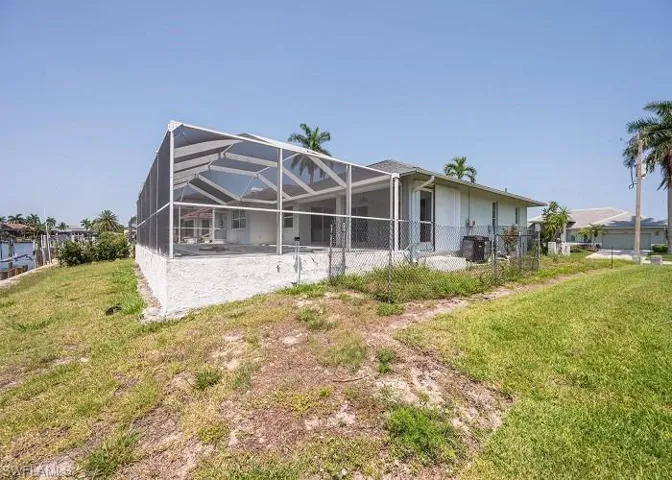 Rear view of property featuring a yard and glass enclosure