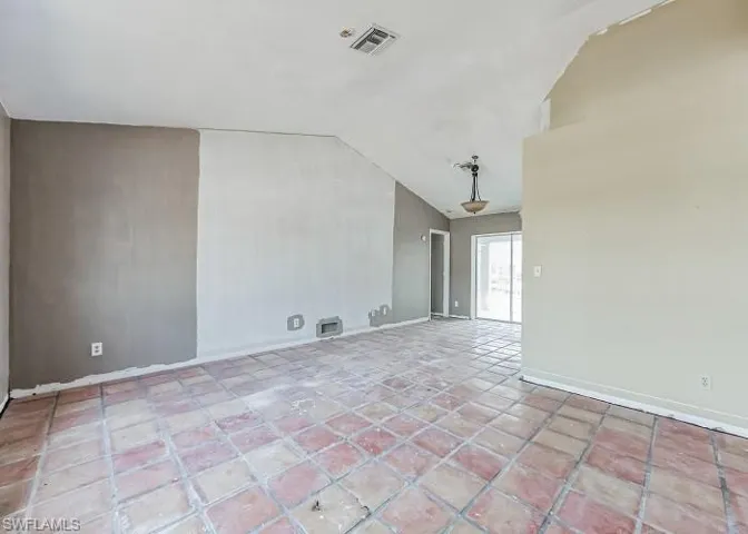 Tiled spare room featuring lofted ceiling
