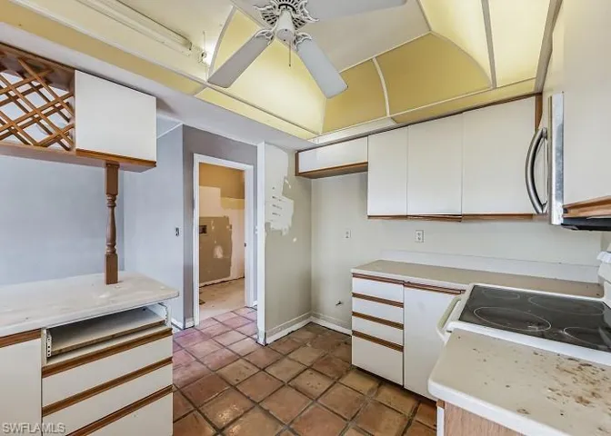 Kitchen featuring white cabinets, stove, dark tile flooring, and ceiling fan