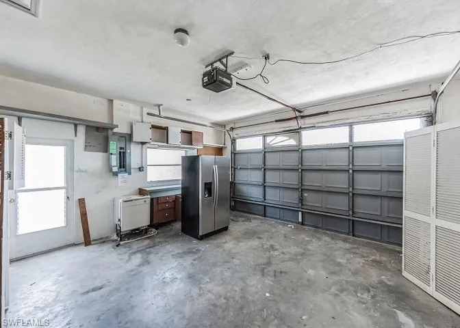 Garage featuring a garage door opener and stainless steel fridge