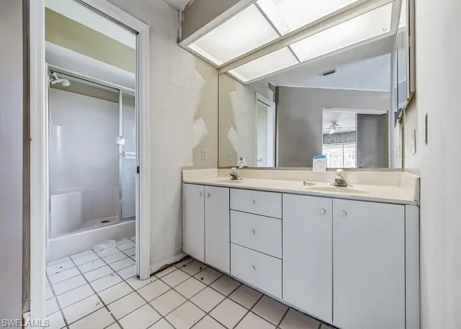 Bathroom with tile floors, walk in shower, oversized vanity, and dual sinks
