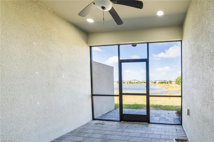 Screened-in lanai featuring a paver floor, ceiling fan, recessed lighting, and a metal-framed screen enclosure overlooking a pond