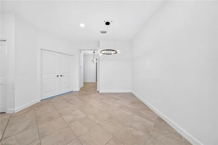 Large-format tile flooring, circular multi-light chandelier, and double-door entry