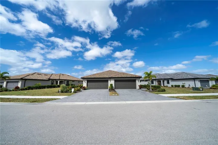 Single-story residence featuring a tile roof, paved driveway, and a two-car garage