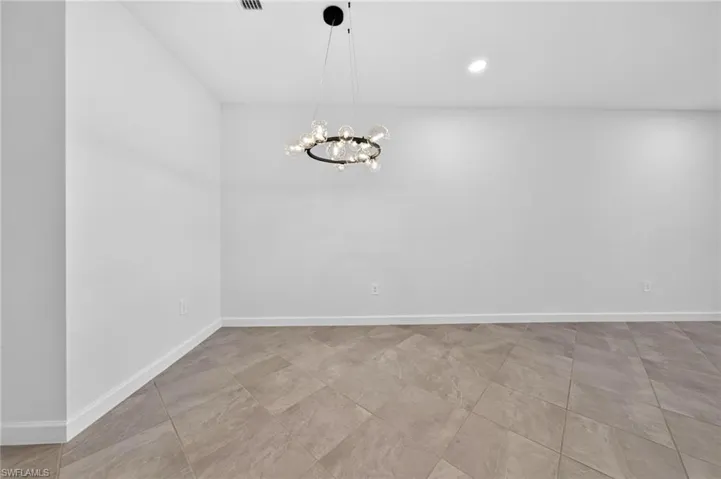 Neutral walls with circular globe chandelier and large-format tile flooring installed on a diagonal pattern