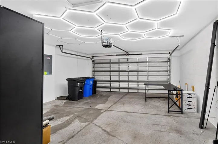 Multi-car garage featuring a honeycomb LED ceiling light system, painted concrete block walls, and a sectional metal garage door