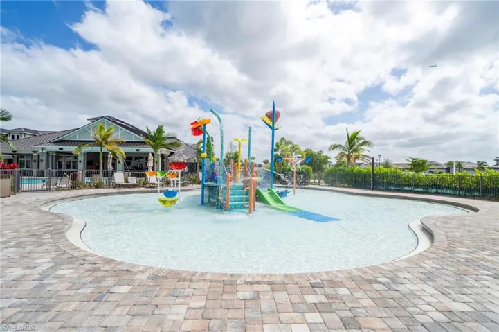 Recreational splash pool featuring a central interactive water structure with integrated slides, zero-entry access, and surrounding paver decking