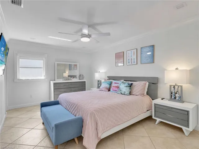 Bedroom with ornamental molding, tile patterned flooring, and ceiling fan