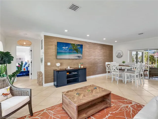 Living room with an accent wall, light tile patterned flooring, recessed lighting, crown molding, and wallpapered walls