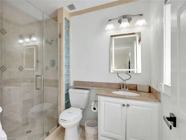 Bathroom with vanity, a shower stall, tile patterned flooring, and a textured wall