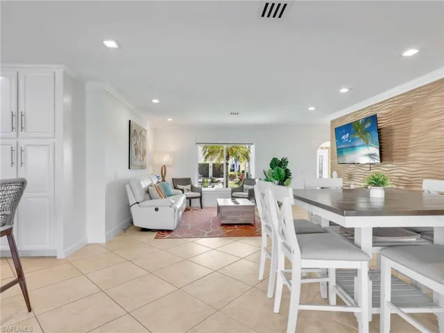 Dining room with light tile patterned floors, recessed lighting, and crown molding