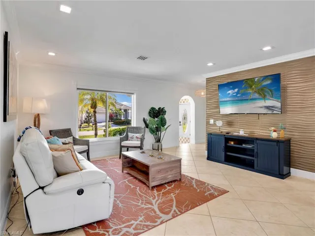 Living area with recessed lighting, an accent wall, light tile patterned floors, and crown molding