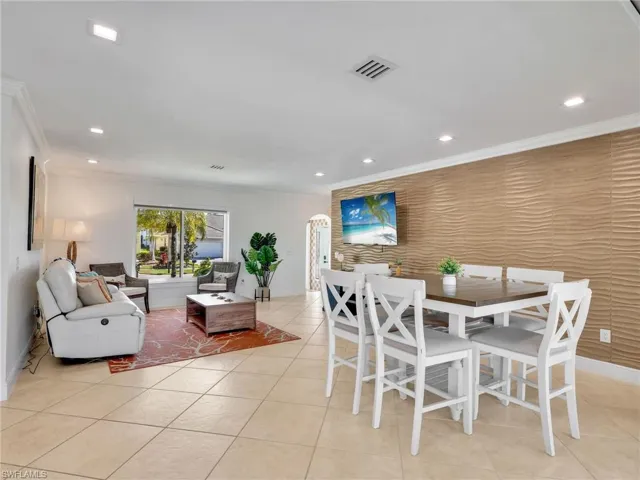 Dining area with an accent wall, recessed lighting, light tile patterned floors, and ornamental molding