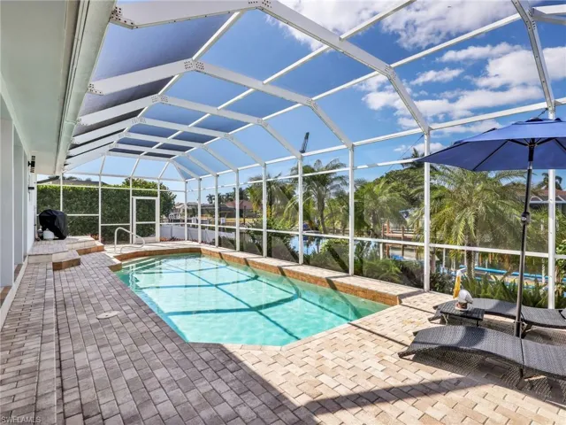 Outdoor pool with a lanai, a sunroom, and a water view