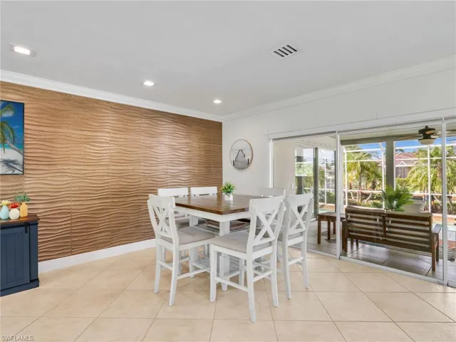 Dining area with an accent wall, recessed lighting, light tile patterned floors, and ornamental molding