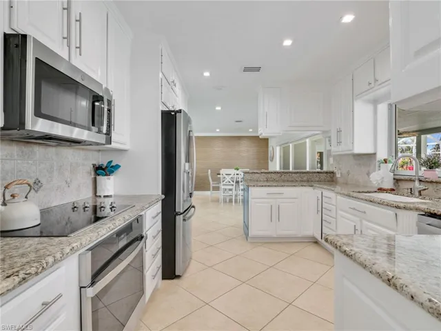 Kitchen with white cabinetry, appliances with stainless steel finishes, light stone countertops, tasteful backsplash, and recessed lighting