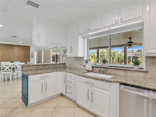 Kitchen with white cabinets, dishwasher, a ceiling fan, light stone countertops, and light tile patterned floors
