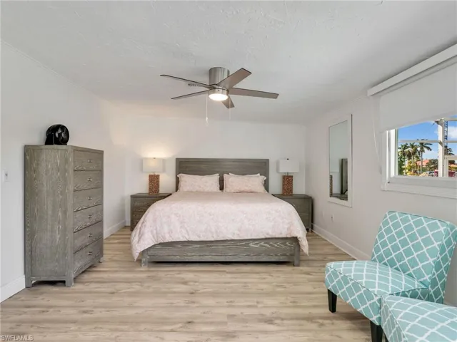 Bedroom with light wood finished floors, ceiling fan, and a textured ceiling