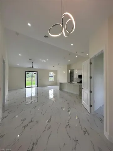 Unfurnished living room featuring hanging lights and light marble finish flooring