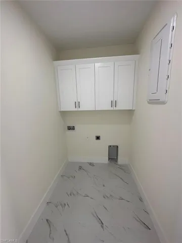 Laundry area featuring electric dryer hookup, light marble finish floors, cabinet space, electric panel, and hookup for a washing machine