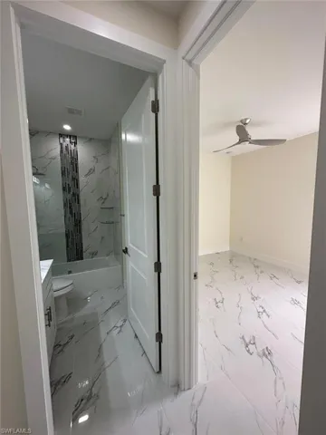 Bathroom with vanity, light marble finish floors, and a ceiling fan
