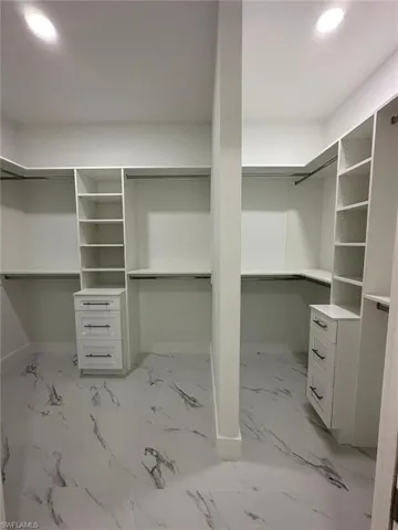 Walk in closet featuring light marble finish flooring