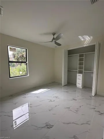 Unfurnished bedroom featuring a closet, ceiling fan, and light marble finish flooring