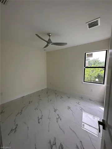 Empty room featuring light marble finish floors and a ceiling fan