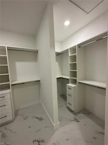 Walk in closet featuring light marble finish flooring