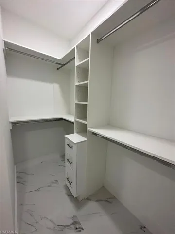 Walk in closet featuring light marble finish floors