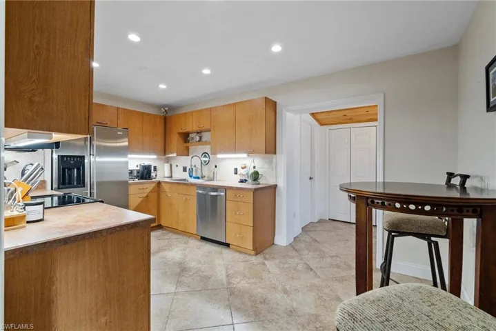 Kitchen featuring light tile patterned floors, appliances with stainless steel finishes, sink, extractor fan, and decorative backsplash