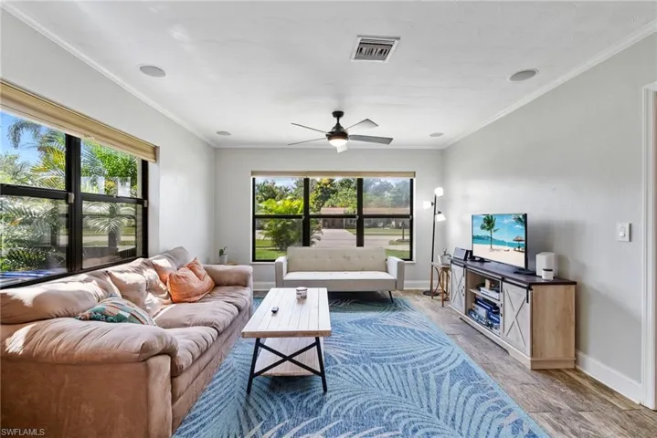 Living room featuring ornamental molding, a wealth of natural light, hardwood / wood-style floors, and ceiling fan