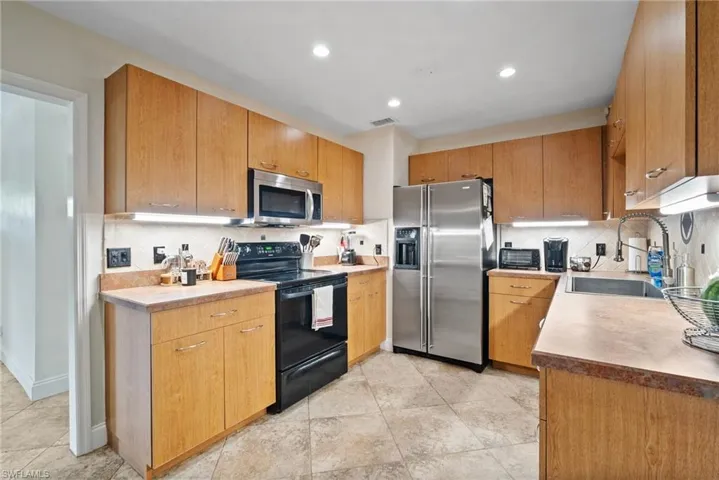 Kitchen with light tile patterned flooring, sink, appliances with stainless steel finishes, and decorative backsplash