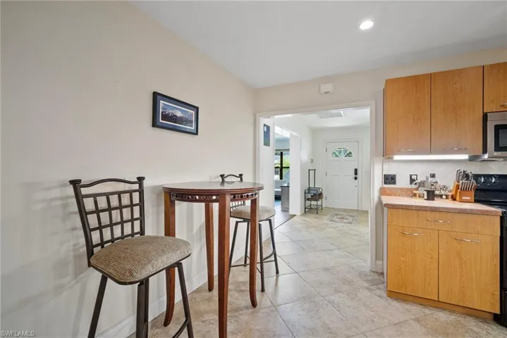 Kitchen featuring black electric range oven, light tile patterned floors, and decorative backsplash