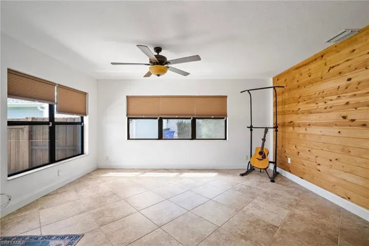 Spare room with plenty of natural light, light tile patterned floors, ceiling fan, and wooden walls