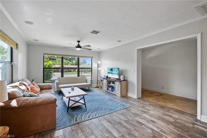 Living room with crown molding, a healthy amount of sunlight, ceiling fan, and hardwood / wood-style flooring