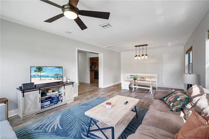 Living room featuring ceiling fan, ornamental molding, and hardwood / wood-style flooring