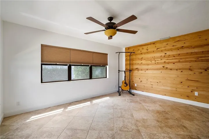 Unfurnished room featuring ceiling fan and wooden walls