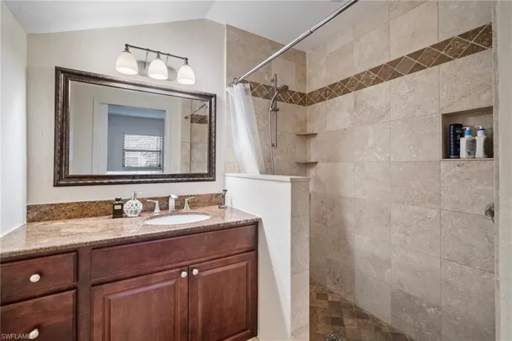 Bathroom featuring vaulted ceiling, curtained shower, and vanity