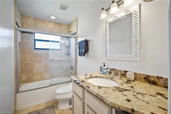 Full bathroom with combined bath / shower with glass door, vanity, toilet, and tile patterned floors