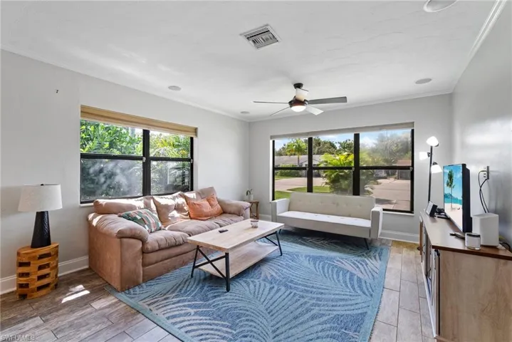 Living room with crown molding, hardwood / wood-style flooring, and ceiling fan