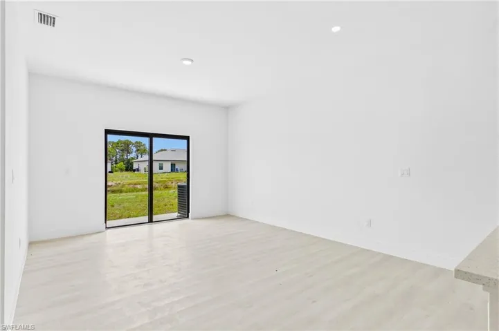 Open-concept living area with high ceilings, vinyl flooring, and abundant natural light flowing throughout the space.
