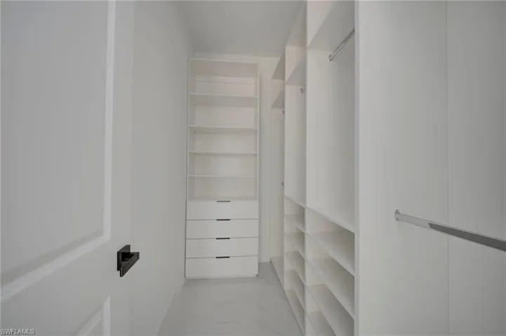 Walk in closet with light marble finish floors