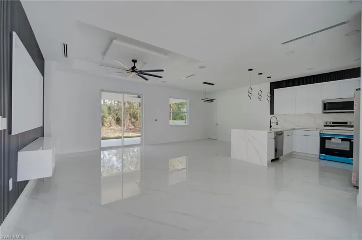 Kitchen featuring open floor plan, white cabinetry, stainless steel appliances, modern cabinets, and light stone counters