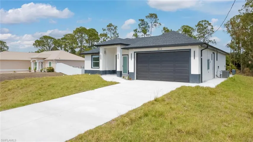 View of front of property with a front yard, an attached garage, stucco siding, driveway, and a shingled roof