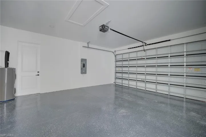 Garage with electric panel, electric water heater, and a garage door opener