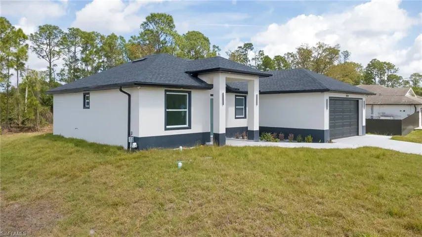 View of front facade with a front yard, an attached garage, stucco siding, concrete driveway, and a shingled roof