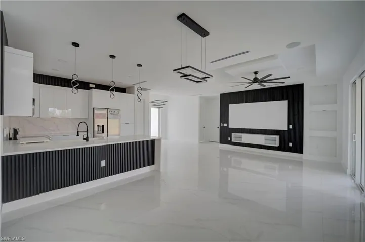 Kitchen featuring white cabinets, hanging light fixtures, stainless steel refrigerator with ice dispenser, and a peninsula