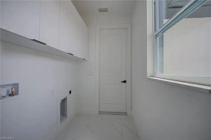 Laundry room featuring washer hookup, cabinet space, light marble finish flooring, and electric dryer hookup