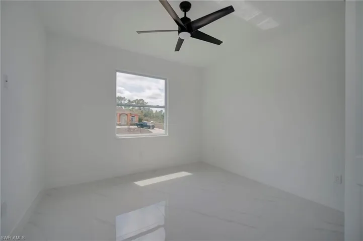 Unfurnished room with light marble finish floors and a ceiling fan